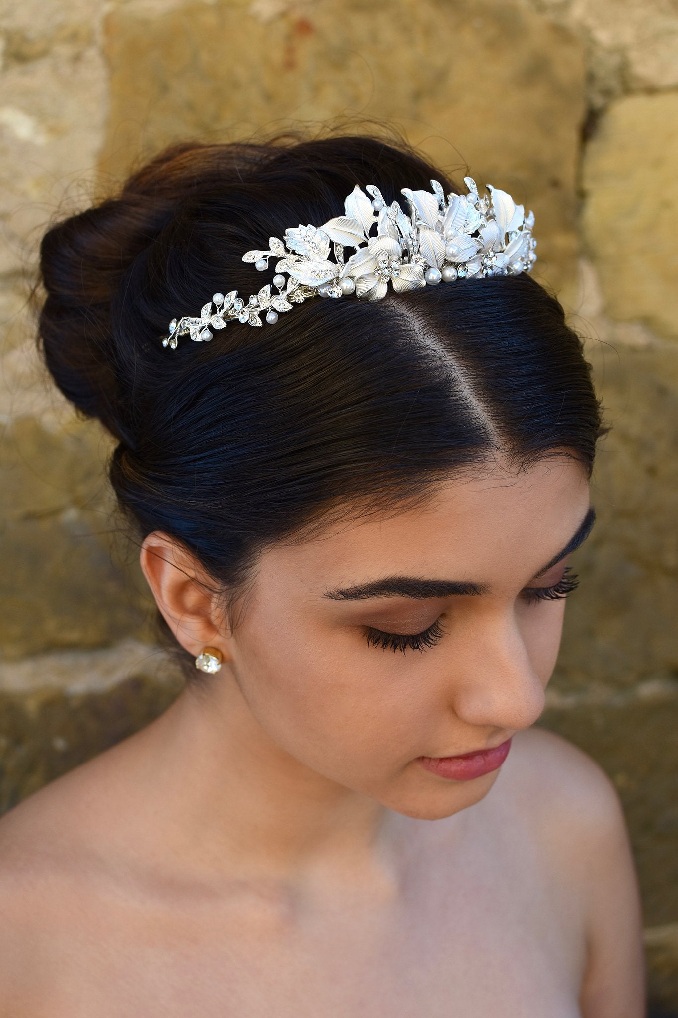 Dark haired bride wears a low silver tiara with a stone wall background