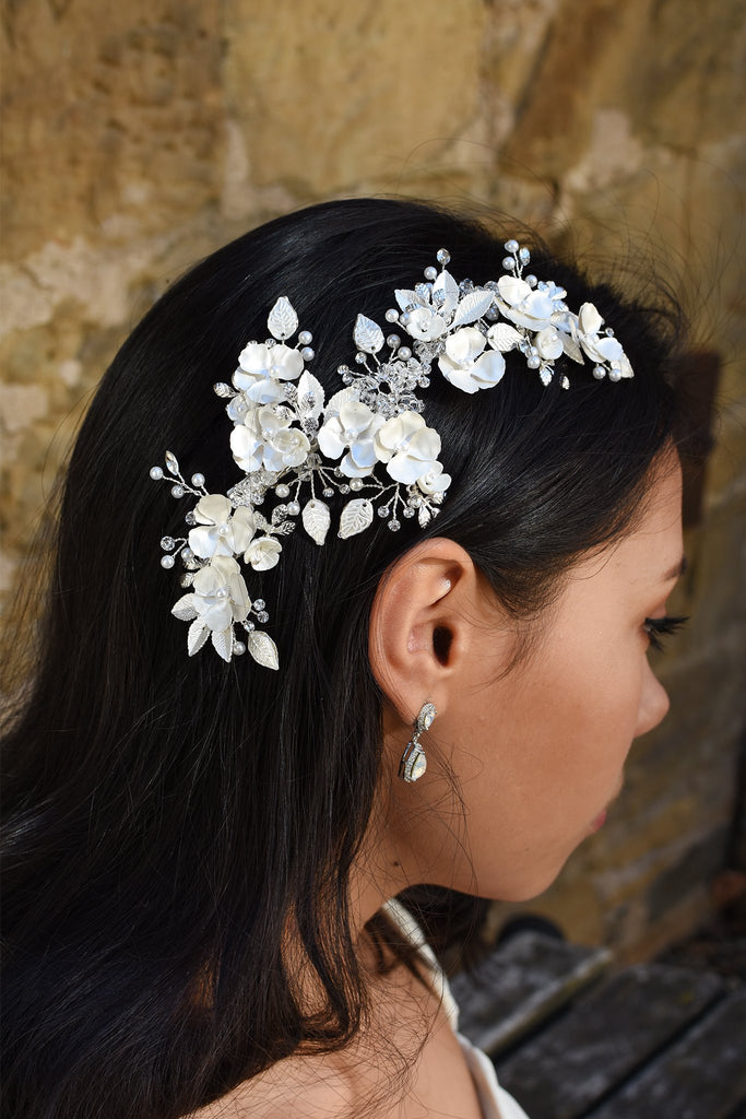 A Dark haired model wears a long side comb with flowers and a small earring