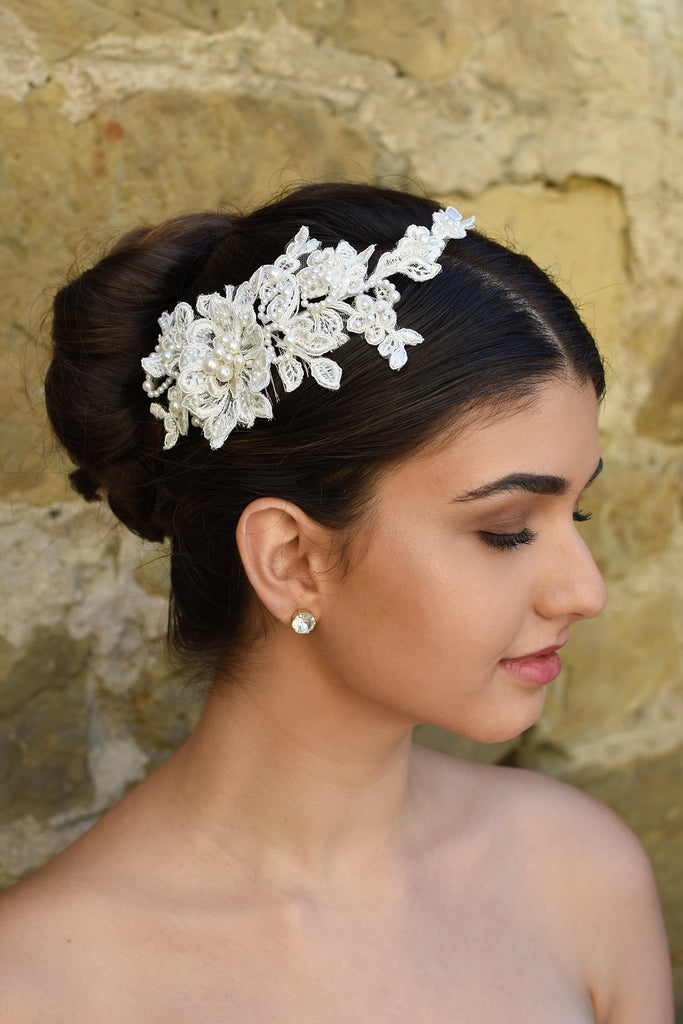 Delicate Lace side comb with pearls worn by a bride in front of a stone wall