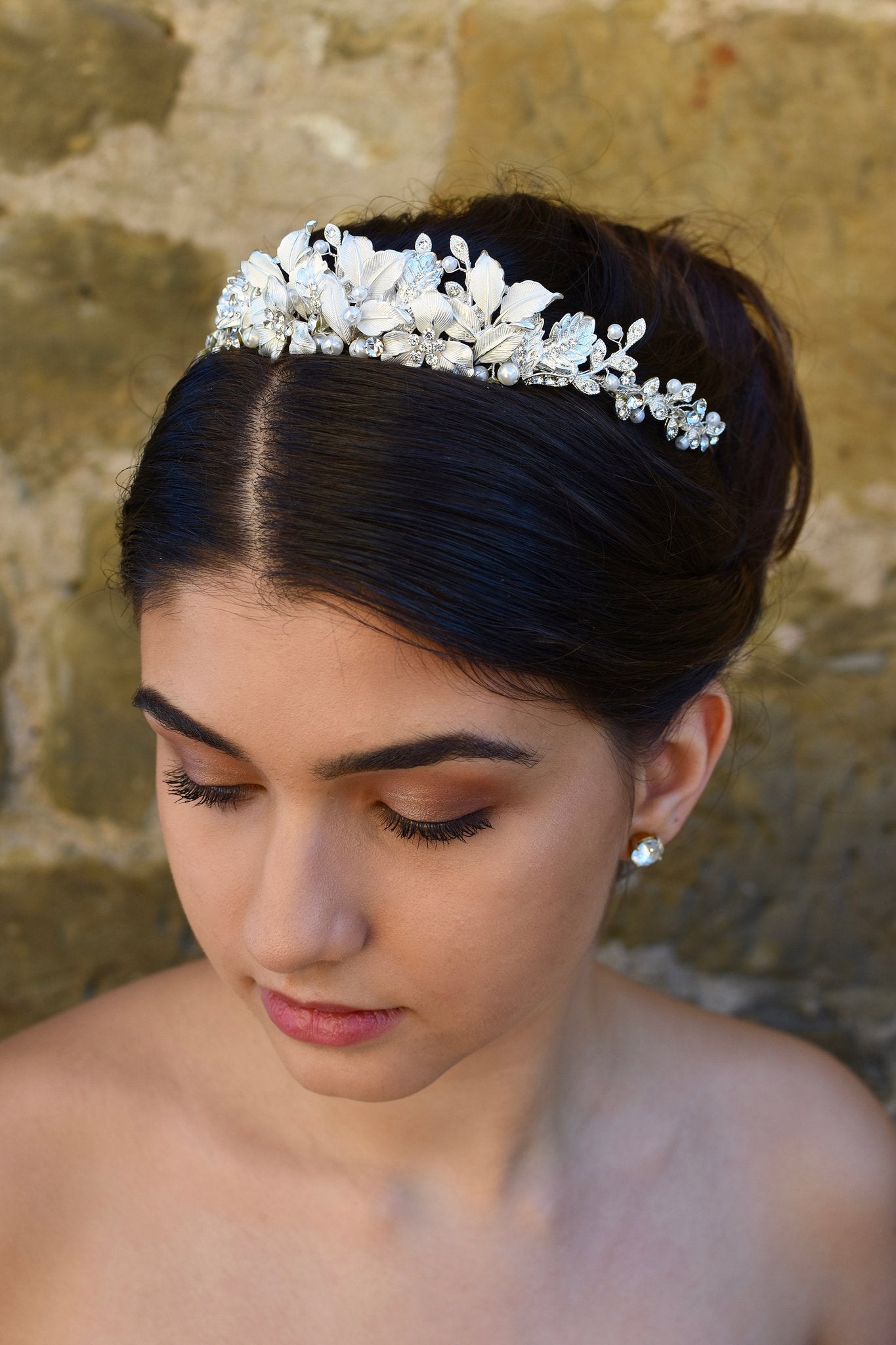 Dark haired bride wears a low silver tiara with a stone wall backdrop