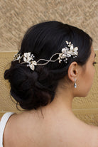 A dark haired model with curly hair wears a Gold vine at the back of her head with a stone background